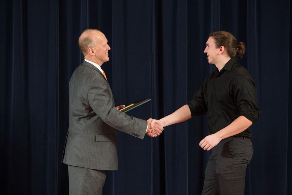 Doctor Potteiger shaking hands with an award recipeint in a black button down